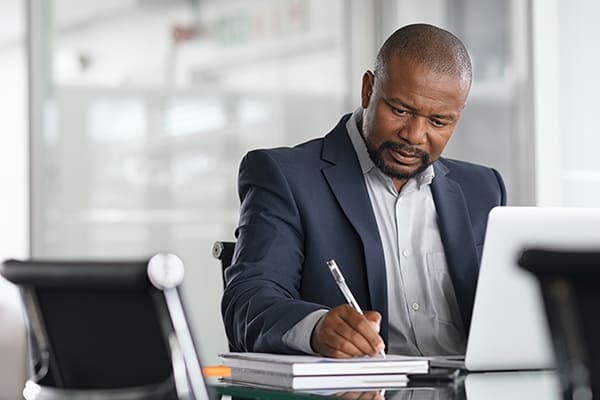business-man-writing-summary-at-desk-with-pen