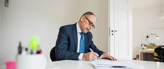 businessman-writing-summary-documents-at-desk